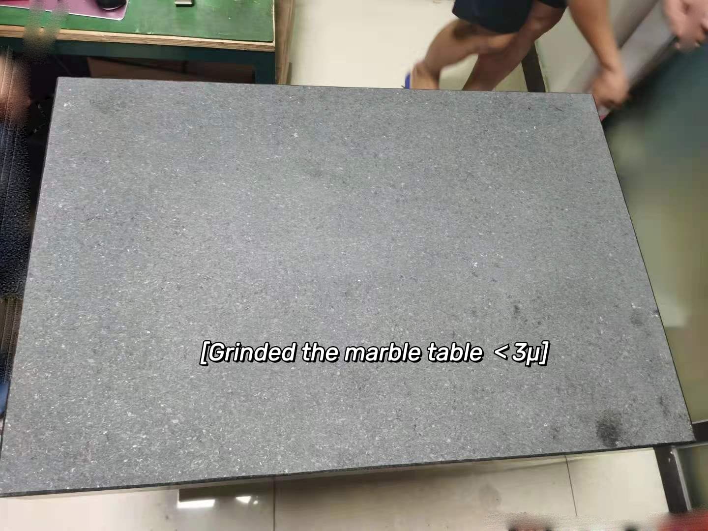 Technician performing maintenance on a marble table used in CNC machining.